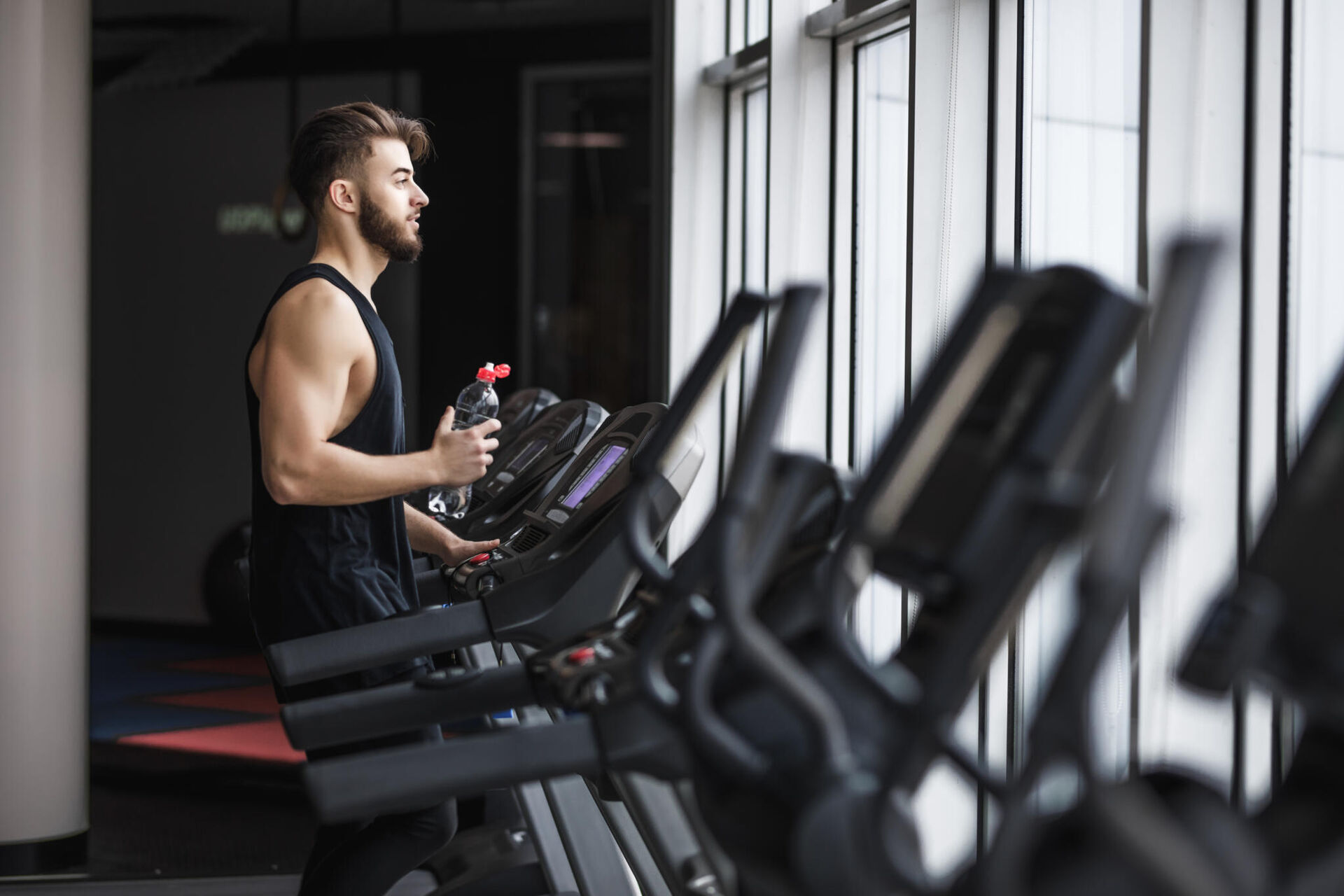 portrait-young-sportsman-making-cardio-workout-drinking-water-gym